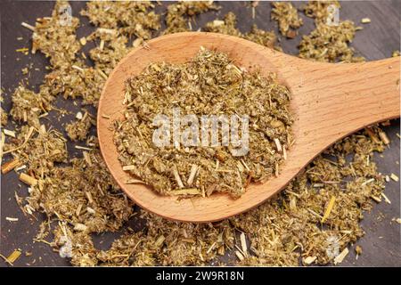 Getrocknete Artemisia vulgaris oder Beifuß-Kraut in rustikalem Löffel. Pflanzliche Arzneimittelkomponente Stockfoto