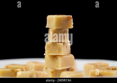 Geschnittenes typisches spanisches Nougatturron mit Mandeln auf schwarzem Hintergrund. Stockfoto