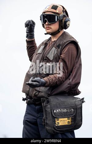 Der Luftfahrt-Strukturmechaniker Airman Apprentice Turner Mulhall, der der ÒBlacklionsÓ of Strike Fighter Squadron (VFA) 213 zugeordnet ist, signalisiert während der Startkontrollen auf dem Flugdeck des weltweit größten Flugzeugträgers USS Gerald R. Ford (CVN 78), 7. Dezember 2023. Die Gerald R. Ford Carrier Strike Group ist derzeit im Mittelmeer tätig. Die USA unterhalten nach vorne entsandte, bereitwillige und positionierte Kräfte, um Aggressionen abzuschrecken und Sicherheit und Stabilität auf der ganzen Welt zu unterstützen. (Foto der US Navy von Simon Pike, Spezialist für Massenkommunikation, 3. Klasse) Stockfoto