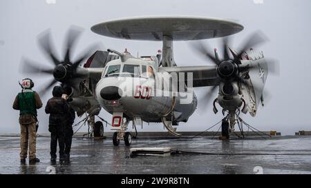 Eine E-2D Hawkeye, die an den „Bear Aces“ der Airborne Command and Control Squadron (VAW) 124 befestigt ist, spuckt am 10. Dezember 2023 auf dem Flugdeck des weltweit größten Flugzeugträgers USS Gerald R. Ford (CVN 78). Die Gerald R. Ford Carrier Strike Group ist derzeit auf Anweisung des Verteidigungsministers im Mittelmeer tätig. Die USA unterhalten nach vorne entsandte, bereitwillige und positionierte Kräfte, um Aggressionen abzuschrecken und Sicherheit und Stabilität auf der ganzen Welt zu unterstützen. (Foto der U.S. Navy von Mass Communication Specialist 3rd Class Maxwell Orlosky) Stockfoto