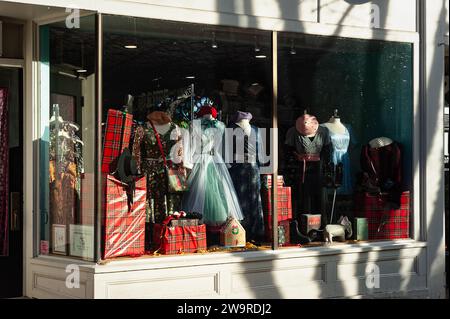 Salem, Massachusetts – Ein kontrastreicher Blick auf ein Bekleidungsgeschäft mit Vintage-inspirierter Kleidung in einem Schaufenster, das von Geschenkverpackungen umgeben ist Stockfoto