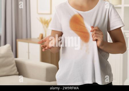 Frau zeigt Flecken von Kaffee auf ihrem Hemd drinnen, Nahaufnahme. Leerzeichen für Text Stockfoto
