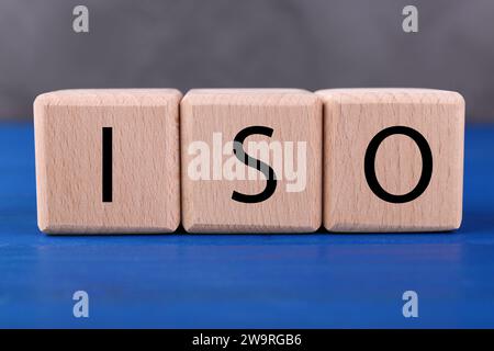 Internationale Organisation für Normung. Würfel mit der Abkürzung ISO auf blauem Holztisch, Großansicht Stockfoto