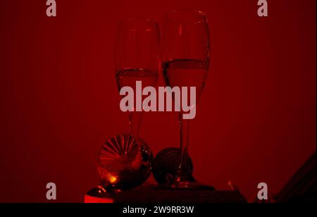 Roter Hintergrund, zwei Stielgläser Champagner, Weihnachtsschmuck Stockfoto