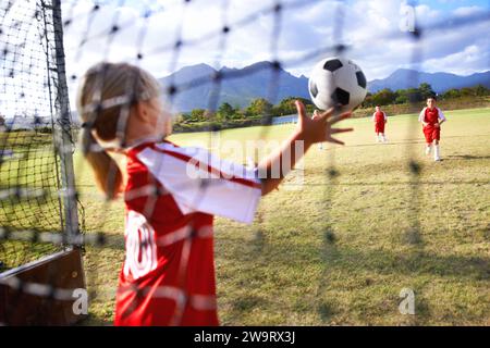 Mädchen, Fußball und Ball mit Torhüter zum Speichern, Match oder Spiel vom Torwart auf dem Außenfeld. Ein Team von Fußballspielern, die zusammen spielen Stockfoto