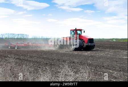 Traktor-Grubber auf dem Feld, Arbeit von Landmaschinen an einem Frühlingstag. Vorbereitung des Bodens für die Aussaat. Stockfoto