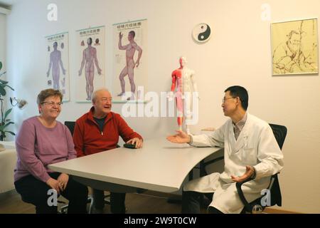 Schaffhausen, Schweiz. Dezember 2023. Der Praktizierende Zhang Zhitai (R) kommuniziert mit seinem Patienten Mogel (C) nach einer Behandlung mit traditioneller Chinesischer Medizin (TCM) in der TCM-Stadtklinik in Schaffhausen, Schweiz, 11. Dezember 2023. ZUM THEMA „Feature: Traditionelle chinesische Medizin in der Schweiz“ Credit: Wang Qibing/Xinhua/Alamy Live News Stockfoto