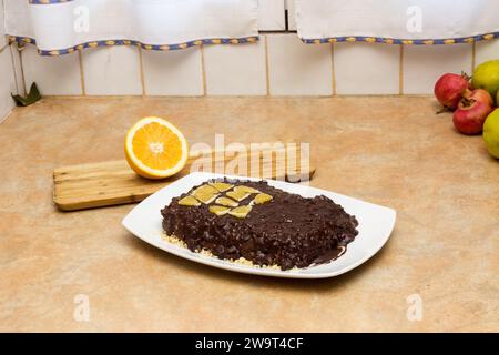 Schokoladenkuchen mit Dreiecken von frischem Orange auf rustikalem Raum, Küchenzeile mit einer halben Orange auf einem hölzernen Schneidebrett und Kopierraum. Feiertagsrezept Stockfoto