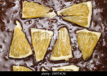 Nahaufnahme von Orangensegmenten auf einem Schokoladen-Kakaokuchen mit Mandeln. Texturen und Speisen. Stockfoto