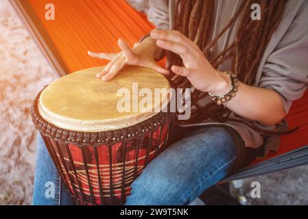 Eine Person mit Dreadlocks spielt Stammesreggae bei kleiner afrikanischer Handtrommel Djembe Stockfoto