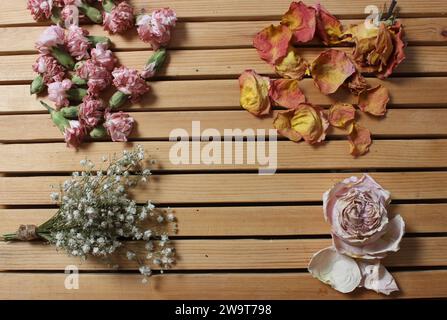 Alte Blumen trocknen auf Holztisch. Zinnien mit Rosen und Nelken Stockfoto