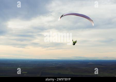 Gleitschirmfliegen auf dem Hügel Pálava in Tschechien. Gleitschirmsilhouette vor Wolken und Himmel. Stockfoto