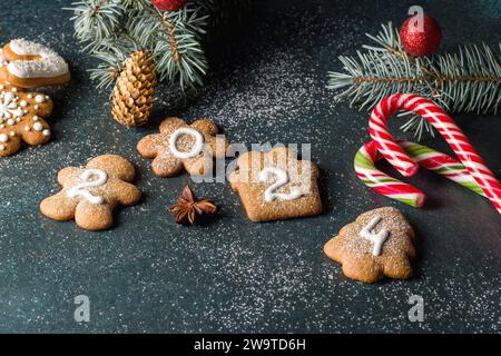 Lebkuchenkekse in Form von Zahlen und 2024. Weihnachtskomposition mit Lebkuchen auf dunklem Hintergrund. Kopierbereich Stockfoto