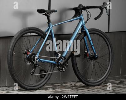 Schotterfahrrad. Glänzendes blaues Fahrrad für Offrad-Radfahren auf grauem Hintergrund. Nahaufnahme. Stockfoto