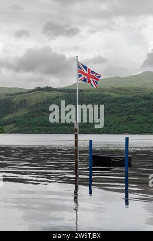 Die Flagge der Union Jack an einem Stange mit einem Boot, das bei Flut im See Loch Sunart in Strontian, Highlands, Schottland gefesselt ist Stockfoto