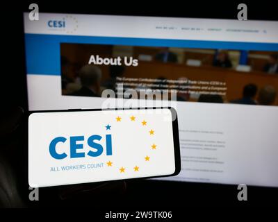 Person mit Smartphone und Logo des Europäischen Gewerkschaftsbundes (CESI) vor der Website. Schwerpunkt auf dem Display des Telefons. Stockfoto