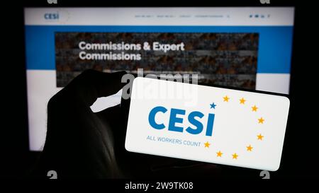 Person, die ein Mobiltelefon mit dem Logo des Europäischen Gewerkschaftsverbands (CESI) vor der Webseite hält. Schwerpunkt auf dem Display des Telefons. Stockfoto