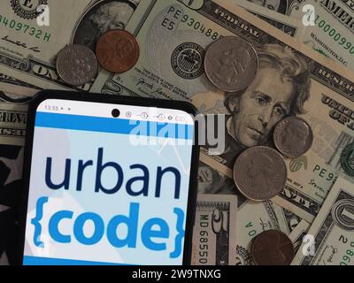 Bayern, Deutschland - 30. Dezember 2023: In dieser Fotoabbildung ist das IBM UrbanCode Logo auf einem Smartphone mit US-Dollar-Note zu sehen Stockfoto