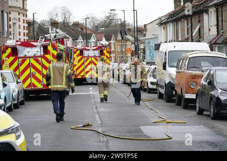 Feuerwehrleute räumen Ausrüstung außerhalb eines Grundstücks an der Sanderstead Road, Croydon, Süd-London, wo zwei Männer starben und zwei weitere in einem kritischen Zustand nach einem Hausbrand am Freitagabend zurückblieben. Bilddatum: Samstag, 30. Dezember 2023. Stockfoto