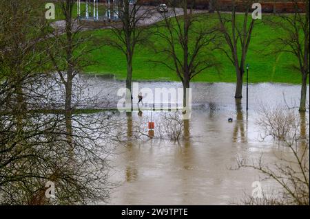 Walker spazieren entlang des Flusses Severn, der seine Ufer geplatzt hat und einen Teil des Quarry Park in Shrewsbury, Shropshire, überschwemmt hat. Stockfoto