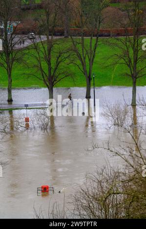 Walker spazieren entlang des Flusses Severn, der seine Ufer geplatzt hat und einen Teil des Quarry Park in Shrewsbury, Shropshire, überschwemmt hat. Stockfoto