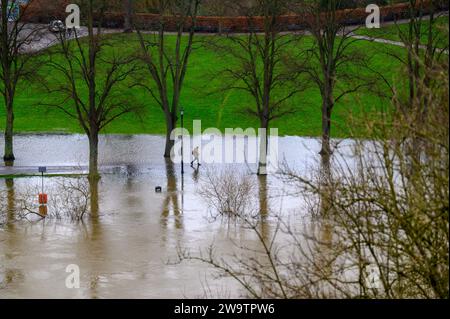 Walker spazieren entlang des Flusses Severn, der seine Ufer geplatzt hat und einen Teil des Quarry Park in Shrewsbury, Shropshire, überschwemmt hat. Stockfoto