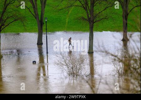 Walker spazieren entlang des Flusses Severn, der seine Ufer geplatzt hat und einen Teil des Quarry Park in Shrewsbury, Shropshire, überschwemmt hat. Stockfoto