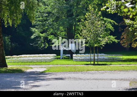 Dekorierter Hochzeitsaltar bei einer Hochzeit im Freien in einem Gartenpark mit weißen Stühlen Stockfoto
