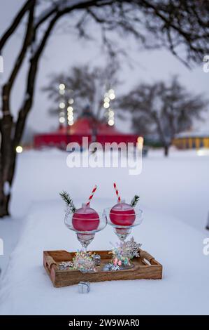 Zwei Margarita-Gläser mit Weihnachtskugeln und Weihnachtsdekoration auf natürlichem Schnee. Kreative Komposition, Urlaubskonzept. Celebratio Stockfoto