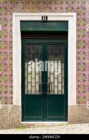 Lissabon traditionelle Tür mit rosa und grünen schönen Azulejo-Fliesen mit grünen und rosa Farben. Die Tür hat die Nummer 44 darüber. Weißer Rahmen. Stockfoto