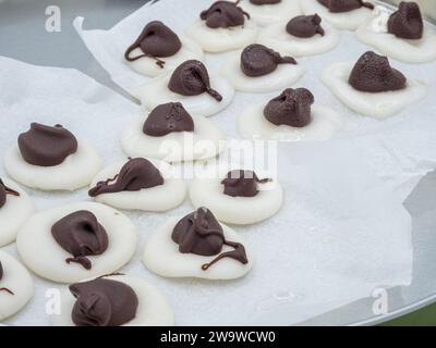 Detaillierte Ansicht mit handgefertigten Minzbonbons, die mit Schokoladentafeln verziert sind, die anmutig auf Pergamentpapier ruhen. Stockfoto