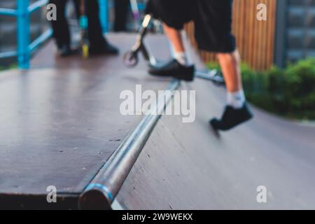 Skatepark mit Kindern auf einem Kick Scooter, die Tricks und Stunts machen, Jungs in einem Skatepark, die bmx-Fahrrad fahren und Skaten fahren, spielen und den Sommer auf dem neuen Widder genießen Stockfoto