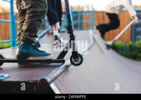 Skatepark mit Kindern auf einem Kick Scooter, die Tricks und Stunts machen, Jungs in einem Skatepark, die bmx-Fahrrad fahren und Skaten fahren, spielen und den Sommer auf dem neuen Widder genießen Stockfoto