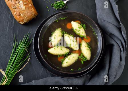 Bayerisches, schwäbisches und österreichisches Gericht – Grießknödel in Gemüsebrühe, serviert mit Vollkornbrötchen Stockfoto