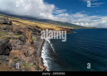 Lavasteilküsten überragen das tiefblaue Wasser von Maui und zeigen die dynamische vulkanische Landschaft der Insel. Stockfoto