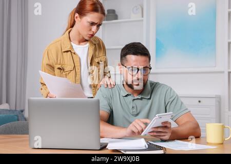 Ein Paar berechnet Steuern für Online-Zahlungen am Tisch im Zimmer Stockfoto