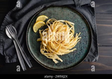 Fettuccine mit Limonen-Mascarponesauce: Ein Teller mit breiten Nudeln, garniert mit Zitronenscheiben Stockfoto