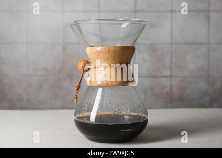 chemex Glaskaffeemaschine mit leckerem Tropfkaffee auf weißem Tisch Stockfoto