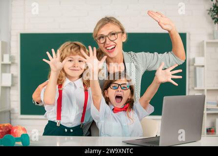 Aufgeregt Lehrer mit einer Schule Kinder lernen am Laptop-Computer, mit Online-Bildung zu studieren. Lehrer und kleine Schüler im Klassenzimmer. Lehrer Stockfoto