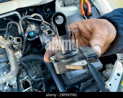 Mechanik, die den Absolutdrucksensor des Ansaugkrümmers (MAP-Sensor ) in der Hand hält, um den MAP-Sensor zu untersuchen und zu reinigen Stockfoto