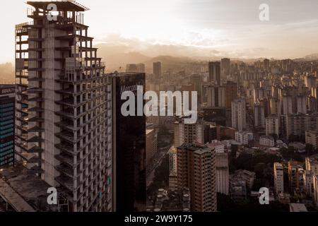 Caracas, Venezuela. Dezember 2023. (ANMERKUNG DER REDAKTION: Bild von einer Drohne) der David Tower ist bei Sonnenuntergang in der Innenstadt zu sehen. Der Wolkenkratzer sollte zum Symbol des Reichtums und Fortschritts Venezuelas werden, wurde aber in den 90er Jahren unvollendet gelassen und jahrelang von obdachlosen Familien besetzt, bis sie 2014 vertrieben wurden. (Foto: Davide Bonaldo/SOPA Images/SIPA USA) Credit: SIPA USA/Alamy Live News Stockfoto