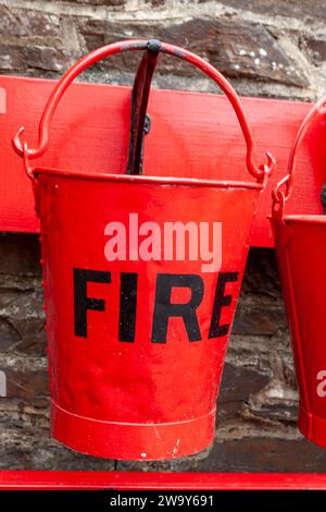 Nahaufnahme eines traditionellen Feuerbehälters auf dem Bahnsteig an der Woody Bay Station an der Lynton and Barnstaple Railway, Devon, Großbritannien Stockfoto