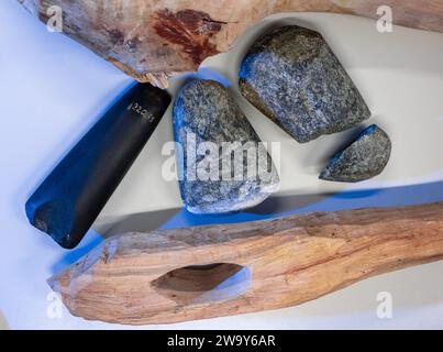 PRODUKTION - 21. Dezember 2023, Sachsen-Anhalt, Halle (Saale): Nachbildungen steinzeitlicher Äxte liegen neben einem Original in einem Labor der Universität Halle (l). Wissenschaftler um die Objektarchäologin Laura Dietrich untersuchen die Spuren von Steinäxten aus der reichen Sammlung des Landesmuseums für Vorgeschichte in Halle. Von jedem der ausgewählten Originalteile wurden Duplikate erstellt. Diese Kopien werden für die Arbeit mit verschiedenen Materialien wie Holz und Knochen verwendet. Die Spuren der Verwendung auf den Kopien werden dann mit den Originalen verglichen. Die Wissenschaftler wollen herausfinden, welche Rolle die Werkzeuge gespielt haben, wenn sich die Menschen niederlassen Stockfoto