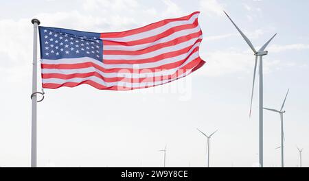 Amerikanische Flagge flattert auf dem Hinterland von Windturbinen. Symbol für nachhaltige Entwicklung Vereinigte Staaten von Amerika. Stockfoto