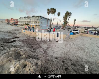 Dezember 30, 2023, Santa Barbara/Ventura, Kalifornien, USA: 30. Dezember, bei Ebbe: Dutzende von Menschen aus ganz Südkalifornien machten sich auf den Weg, um dem Ort in Ventura zu ehren, wo am Donnerstag, 28. Dezember, in Pierpont, Ventura, eine „Schurkenmonsterwelle“ über Sand und Straße schlängelte. fast ein Dutzend Menschen die Straße hinunter gefegt und viele verletzt. die Straßen wurden geputzt, sind aber immer noch schlammig und feucht, und eine Sanddüne wurde von den Crews des County of Ventura gebaut, um zu verhindern, dass weitere Häuser und Geschäfte beschädigt werden: es werden mehr große Wellen und Überschwemmungen erwartet Stockfoto