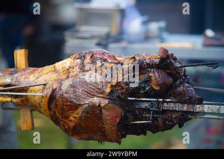 Nahaufnahme einer ganzen Lammkeule, die in einer Szene im Freien mit verschwommenem Hintergrund gebraten wird Stockfoto