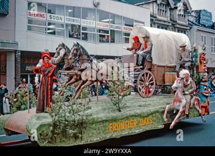 Ein Paradewagen, der am 17. November an der Santa Claus Parade von Eaton in der Yonge Street, Toronto, Ontario, Kanada teilnimmt. 1962. dieser Wagen, die „Frontier Days“, ist mit einem Wagen und Pferden, einem einheimischen Amerikaner zu Pferd und einem Totempfahl ausgestattet. Die jährliche Santa Claus Parade in Toronto (auch bekannt als die ursprüngliche Santa Claus Parade) wurde 1905 erstmals veranstaltet und ist eine der größten in Nordamerika und die älteste Santa Claus Parade der Welt. Es endete früher im Laden in der Innenstadt von Eaton (später Eaton Centre) in der Yonge Street und Queen Street. Stockfoto