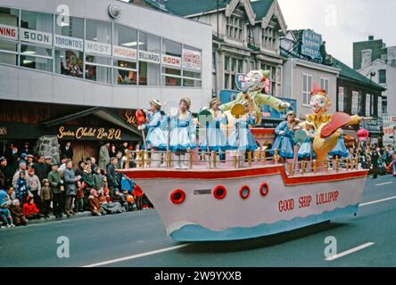 Ein Paradewagen, der am 17. November an der Santa Claus Parade von Eaton in der Yonge Street, Toronto, Ontario, Kanada teilnimmt. 1962. bei diesem Wagen handelt es sich um ein Schiff, „The Good Ship Lollipop“, mit Mädchen in blauen Kostümen, die große Lollies halten, sowie riesigen Pappmaché-Clowns. „On the Good Ship Lollipop“ ist ein Lied von Richard A Whiting und Sidney Clare. Es war das Signature Lied der Kinderdarstellerin Shirley Temple, die es 1934 erstmals in dem Film Bright Eyes sang. Die jährliche Santa Claus Parade (auch bekannt als die ursprüngliche Santa Claus Parade) fand 1905 statt. Stockfoto