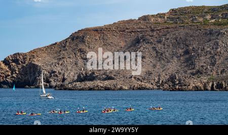 Eine Gruppe von Menschen in Kajaks paddelt um die Bucht in Fornells Menorca Spanien Stockfoto