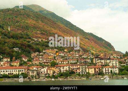 Malerischer Blick auf den wunderschönen Comer See in Italien, umgeben von Bergen, die von farbenfrohen Häusern gesäumt sind und mit Bäumen bedeckt sind, die ihre Farbe ändern Stockfoto